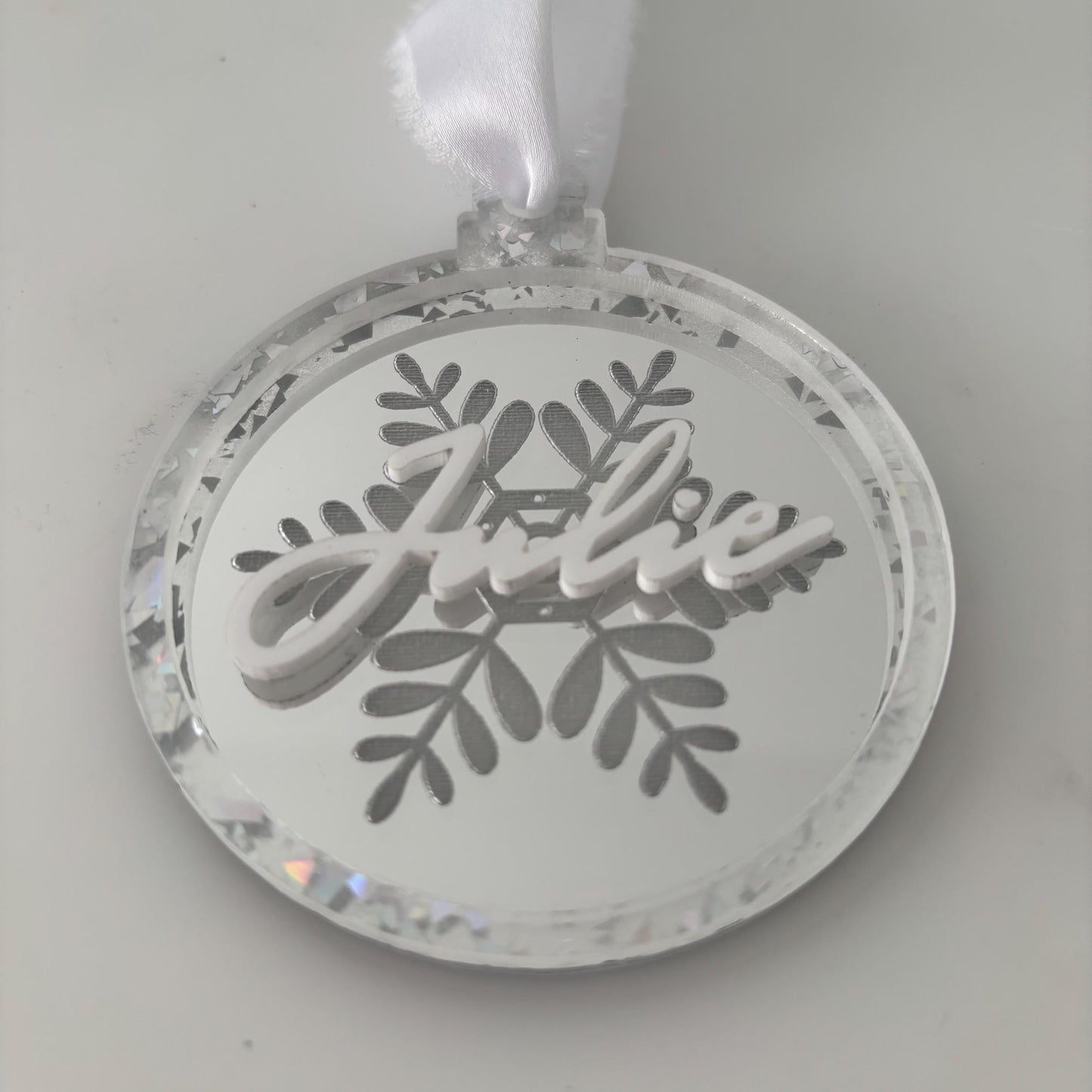 Decorative Christmas ornament with 'Julie' text and snowflake design on a silver background