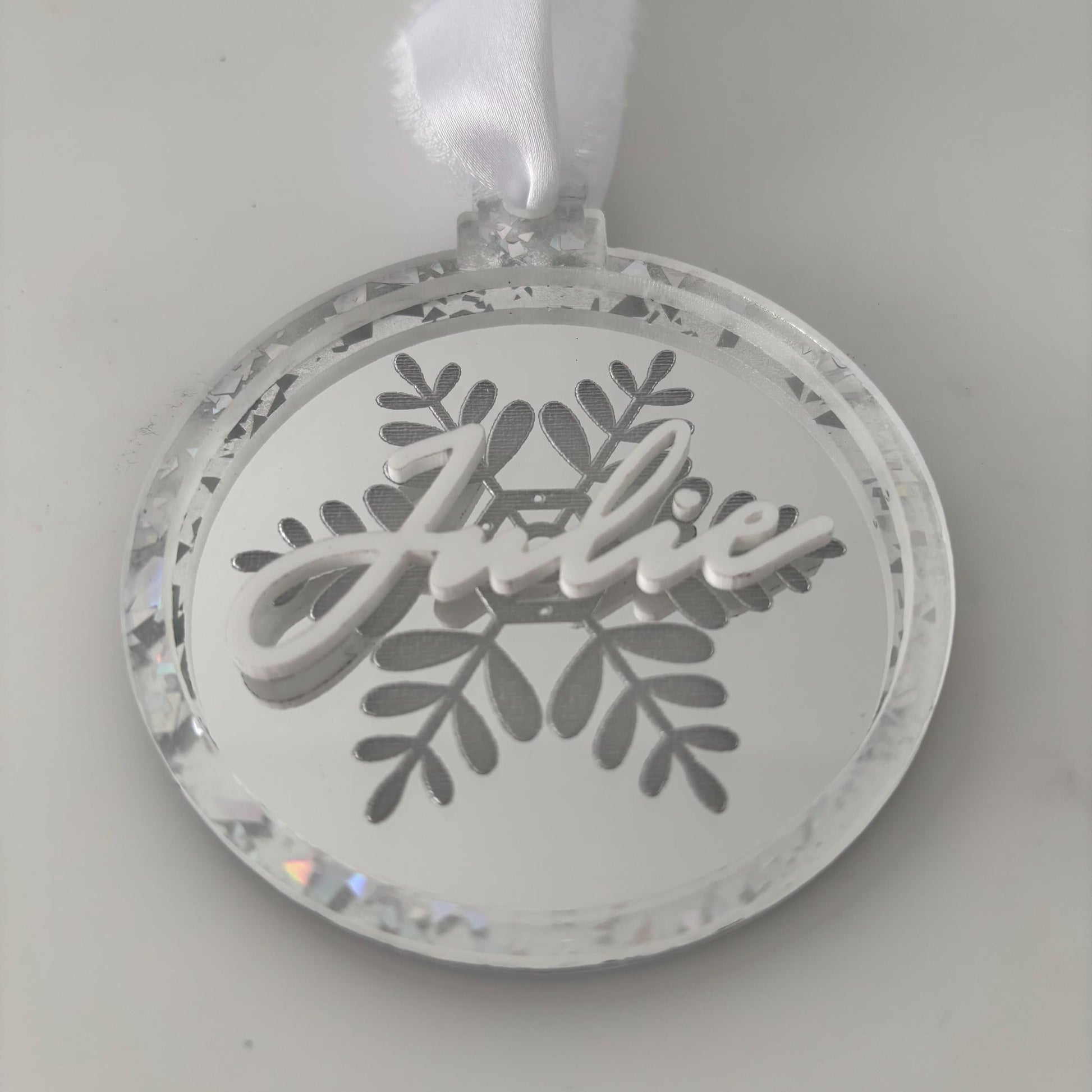 Decorative Christmas ornament with 'Julie' text and snowflake design on a silver background
