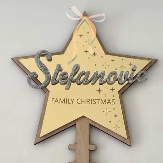 Decorative star-shaped sign with 'Stefanovic Family Christmas' text on a grey background