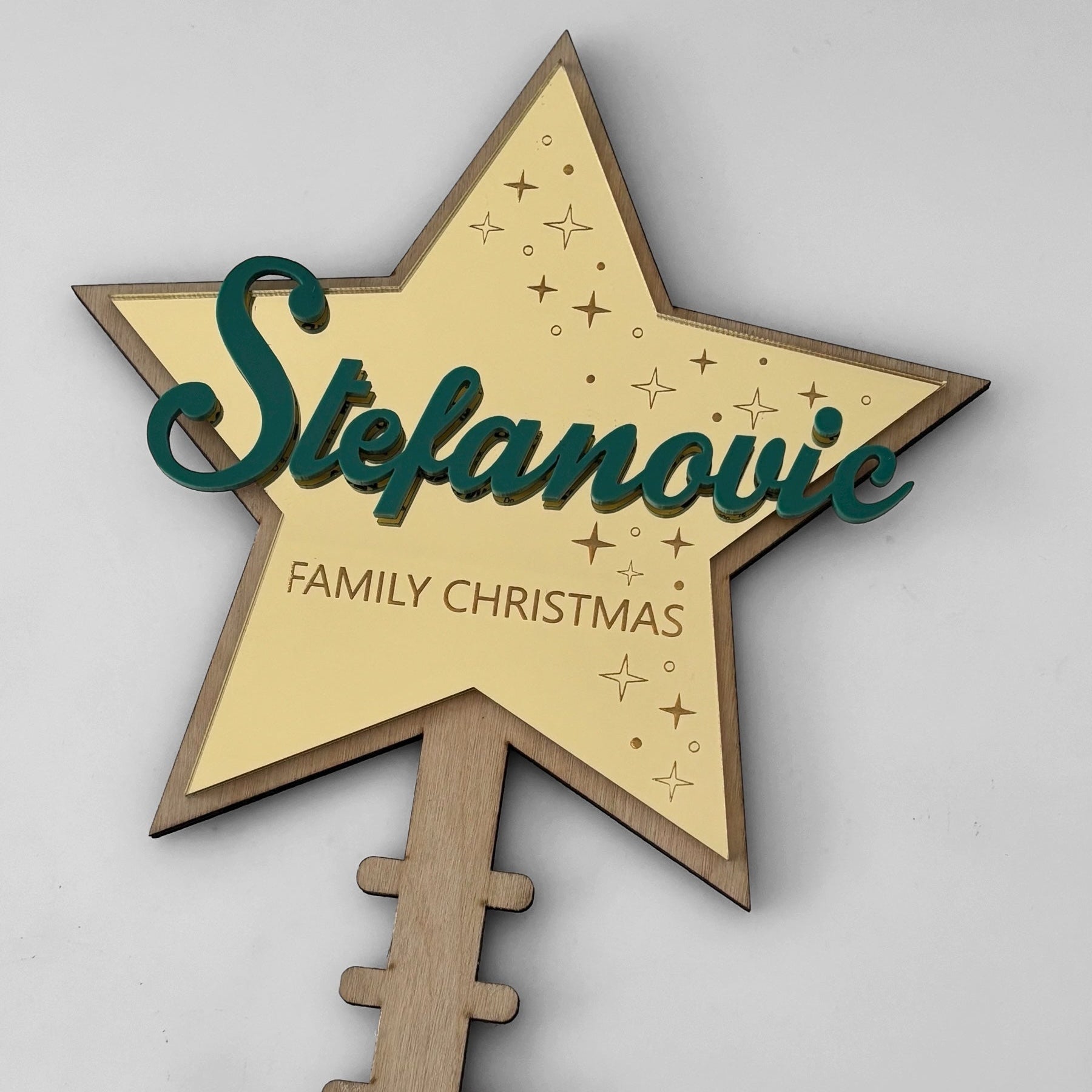 Wooden star-shaped decoration with 'Stefanovic Family Christmas' text on a grey background