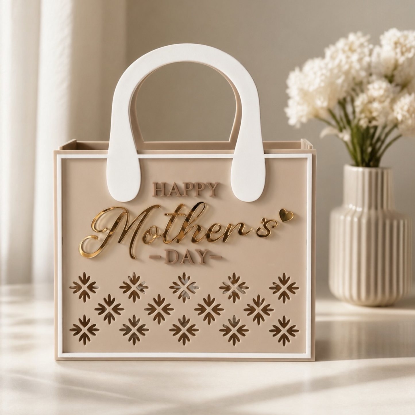 Decorative box with 'Happy Mother's Day' text and floral design, placed on a surface with a vase of flowers in the background.
