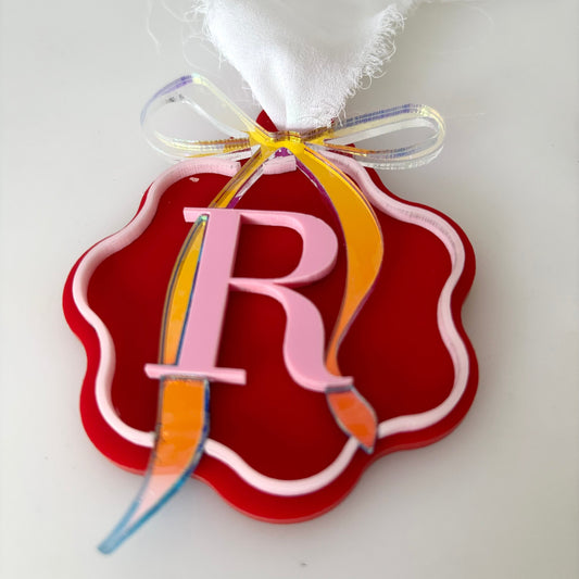 Decorative Christmas bauble with a pink letter 'R' on a red and white background