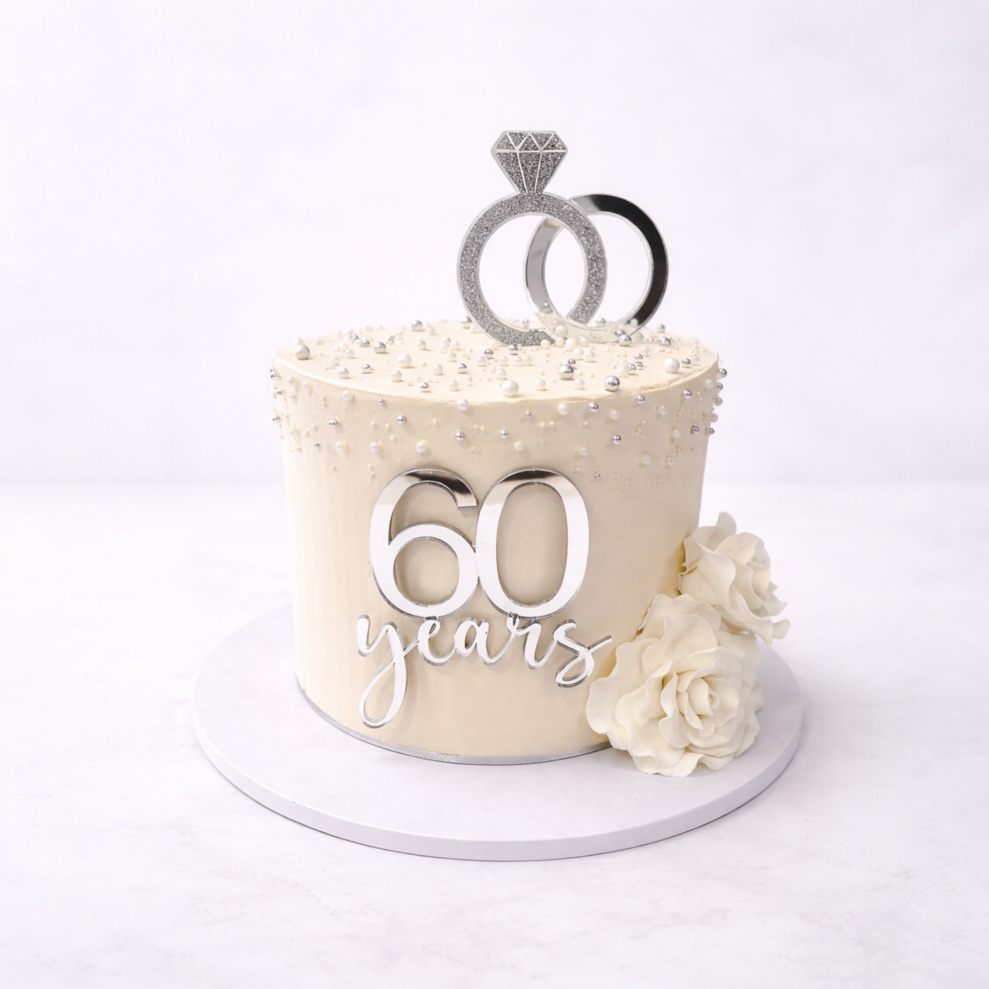 Wedding Anniversary cake with '60 years' and wedding ring topper on a white background