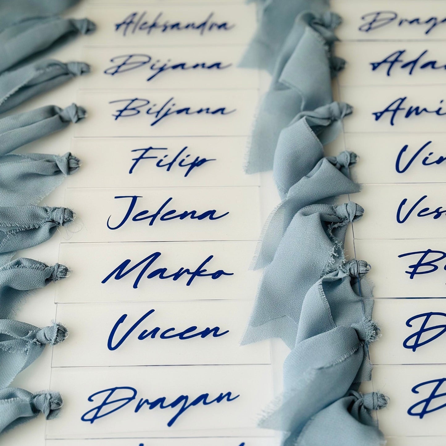 Names written in blue vinyl on acrylic place cards for wedding tables and events.