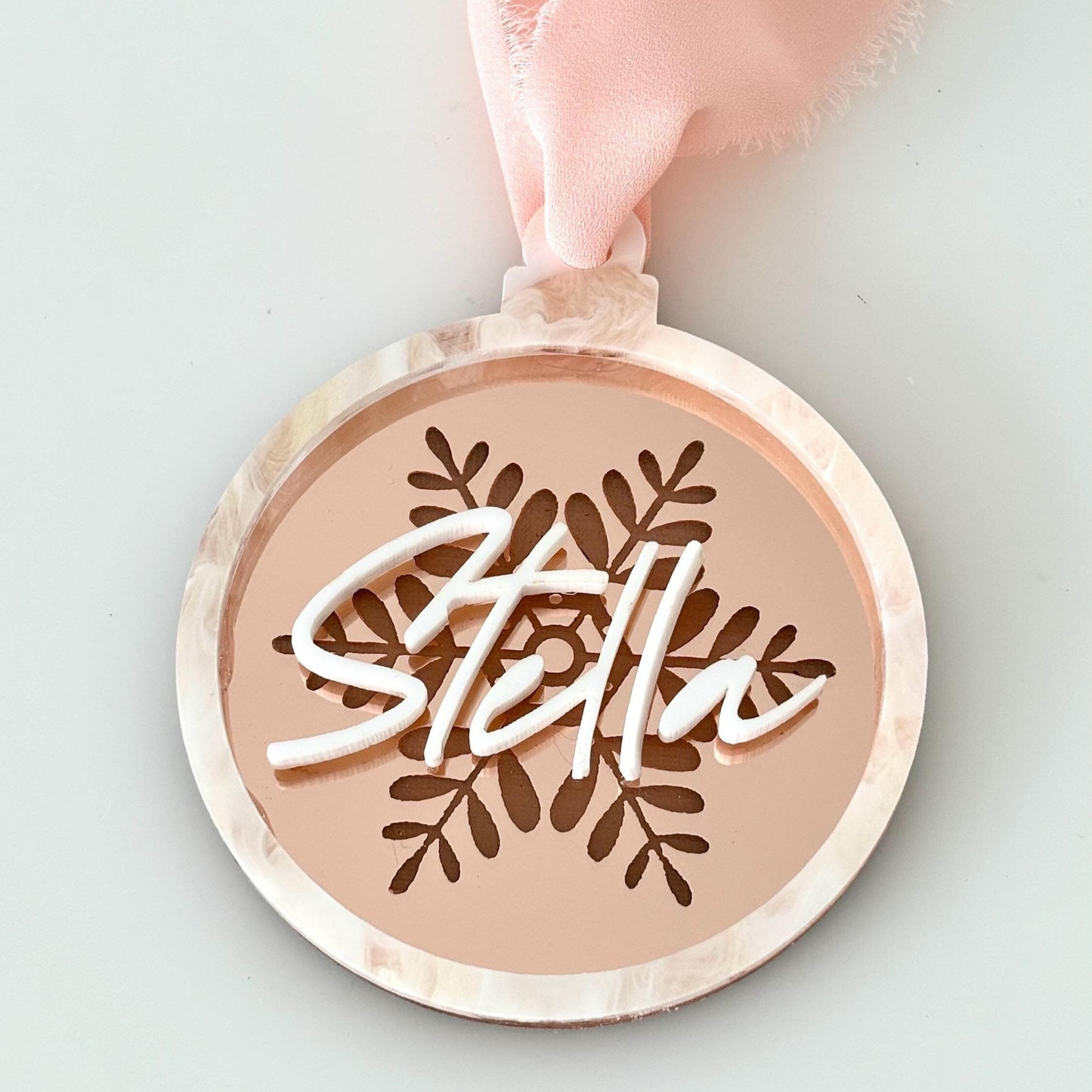 Round acrylic christmas bauble with 'Stella' engraving on a rose gold, snowflake engraved background