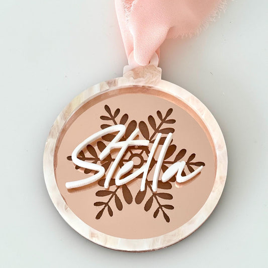 Round acrylic christmas bauble with 'Stella' engraving on a rose gold, snowflake engraved background